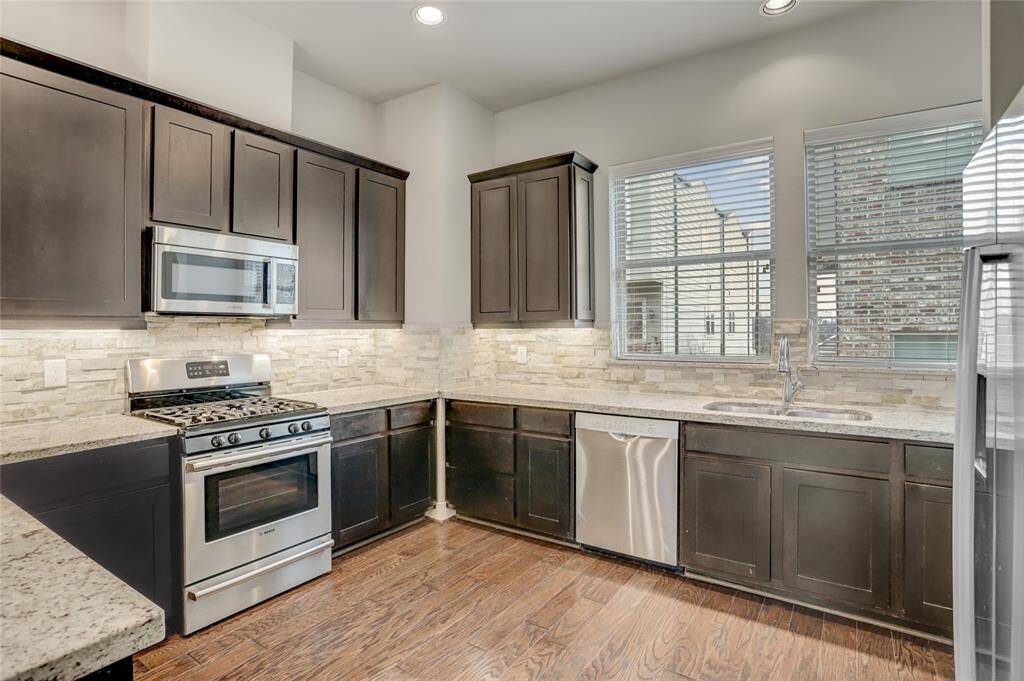 The spacious Kitchen features tons of counterspace, a beautiful stone backsplash, lots of cabinetry (including built-in trash drawer), under cabinet lighting, LED recessed lights, large windows, wood floors and Bosch stainless-steel appliances.
