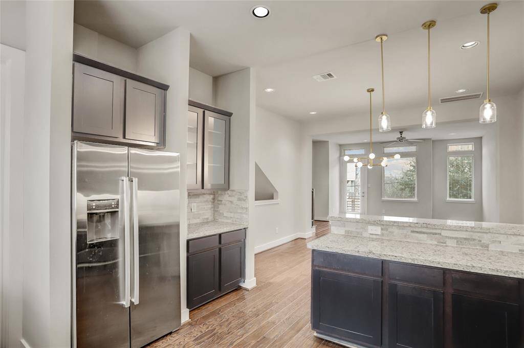 The Kitchen, open to the Dining & Family Rooms, also features recent on-trend pendants (2025), a walk-in pantry, a breakfast bar and a coffee/dry bar with glass-front display cabinets.