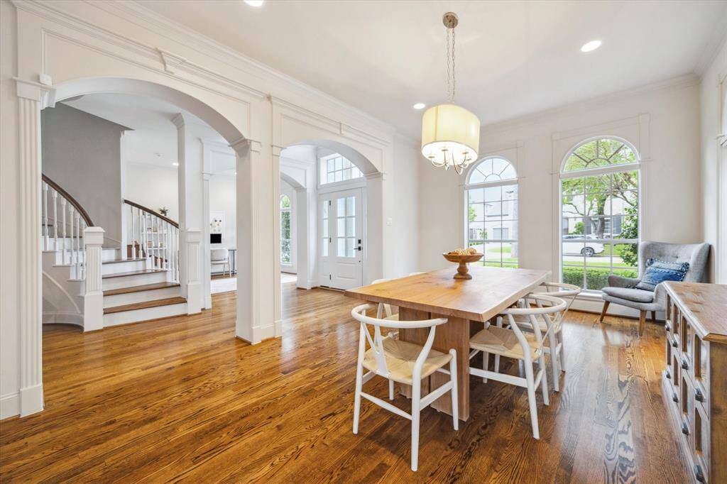 Another view of the dining room reveals its intricate molding, adding a refined touch to the space. Just to the left of the sweeping circular staircase are the coat closet and a well-appointed powder room.