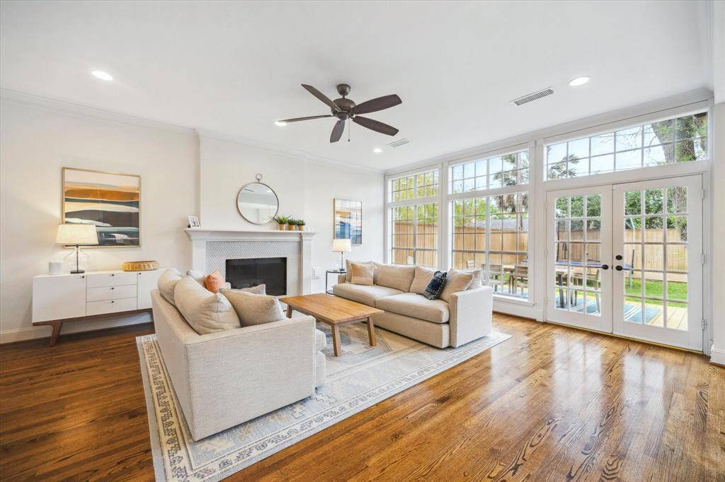 Recessed lighting enhances the open design of the living, kitchen, and breakfast areas, while a gas fireplace adds warmth and charm. A wall of windows frames stunning views of the covered patio and expansive backyard.