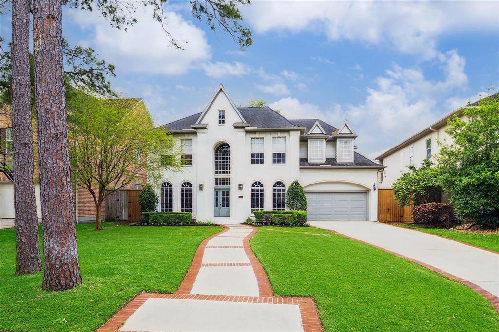 Fantastic curb appeal with a brick-lined front walkway, framed by lush, meticulously manicured landscaping and towering trees!