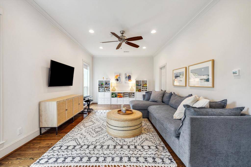 Another perspective of the downstairs bedroom showcases recessed lighting, a ceiling fan, and elegant crown molding and is conveniently located off the kitchen.