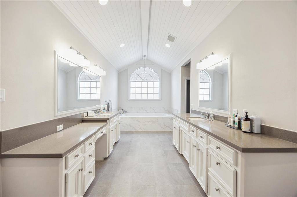 The primary bath offers a spa-like retreat, complete with dual vanities, recessed lighting, exquisite tub, walk-in shower and a beautifully detailed ceiling.