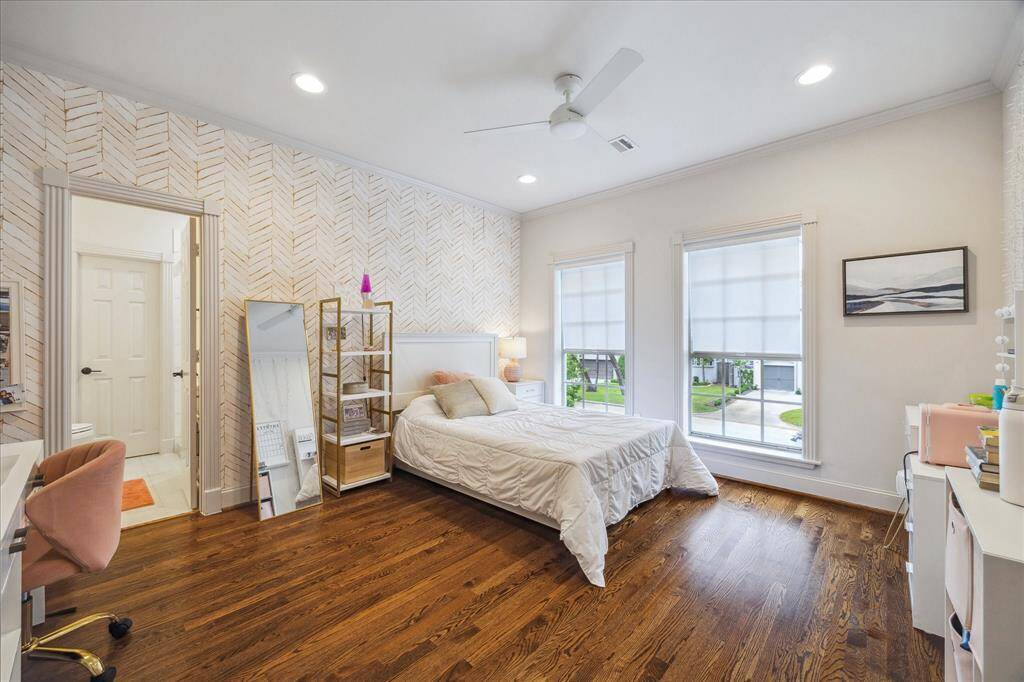 This front bedroom features a striking accent wall, north-facing windows, recessed lighting, and a ceiling fan. The open door leads to the en-suite bathroom, adding convenience and privacy.