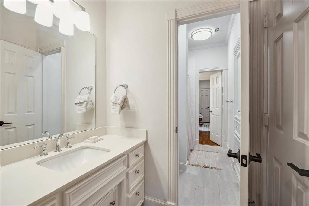 The Jack-and-Jill bathroom features sleek quartz countertops, chrome plumbing fixtures, a tub with a classic subway tile surround, and porcelain flooring.