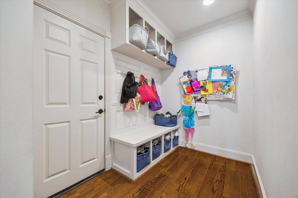 The mudroom is equipped with multiple cubbies and hooks, providing convenient storage for backpacks, jackets, and other everyday items. The door to the left leads to the two-car garage.
