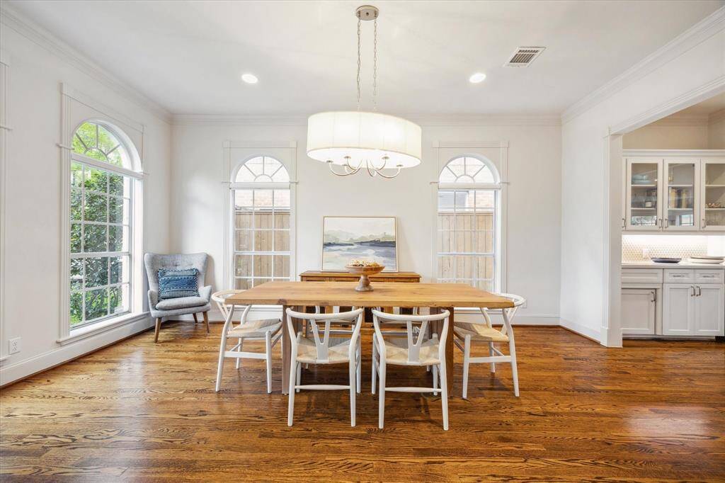 The expansive dining room is elegantly appointed with recessed lighting, chandelier, detailed crown molding and millwork, and large windows that bathe the space in natural light. Conveniently located just off the butler's pantry/wet bar, it’s ideal for effortless entertaining.