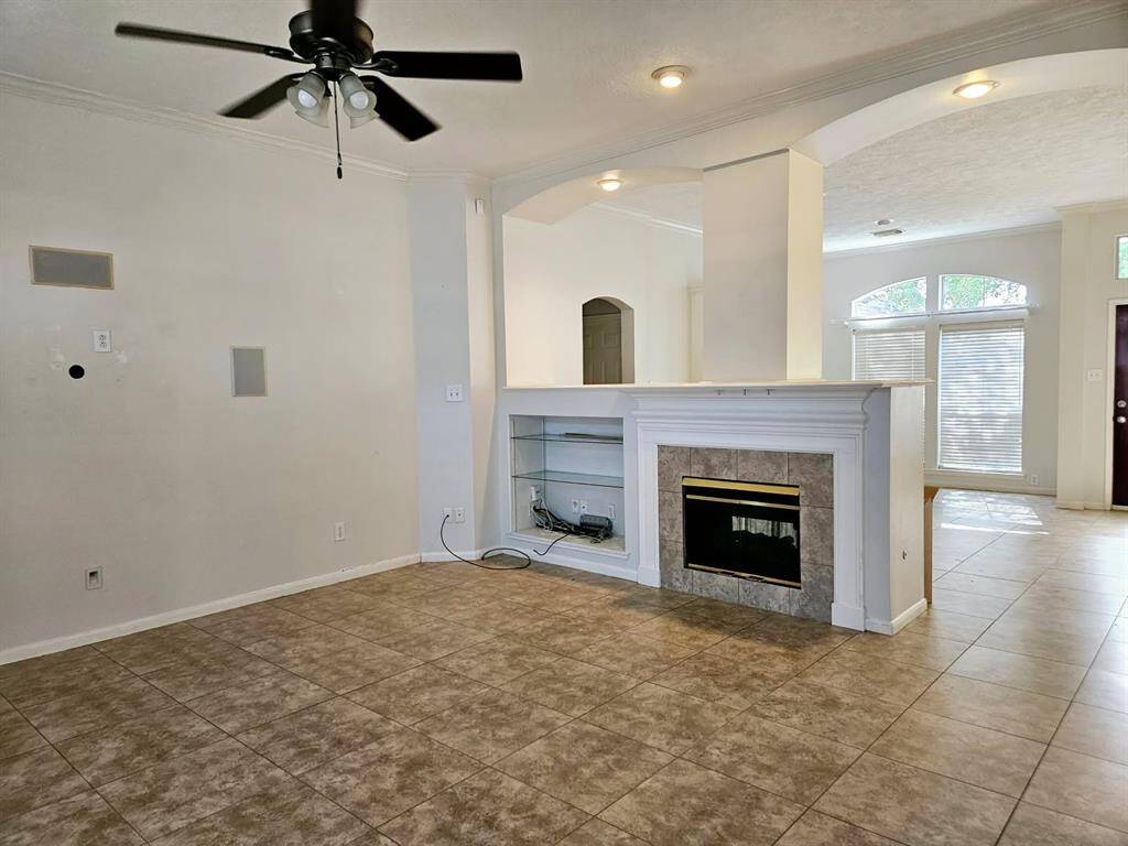 The spacious  living area features a striking double-sided fireplace as its focal point. The open layout allows for seamless connection to the kitchen, while a ceiling fan enhances comfort. This versatile space is designed for both relaxation and lively gatherings.