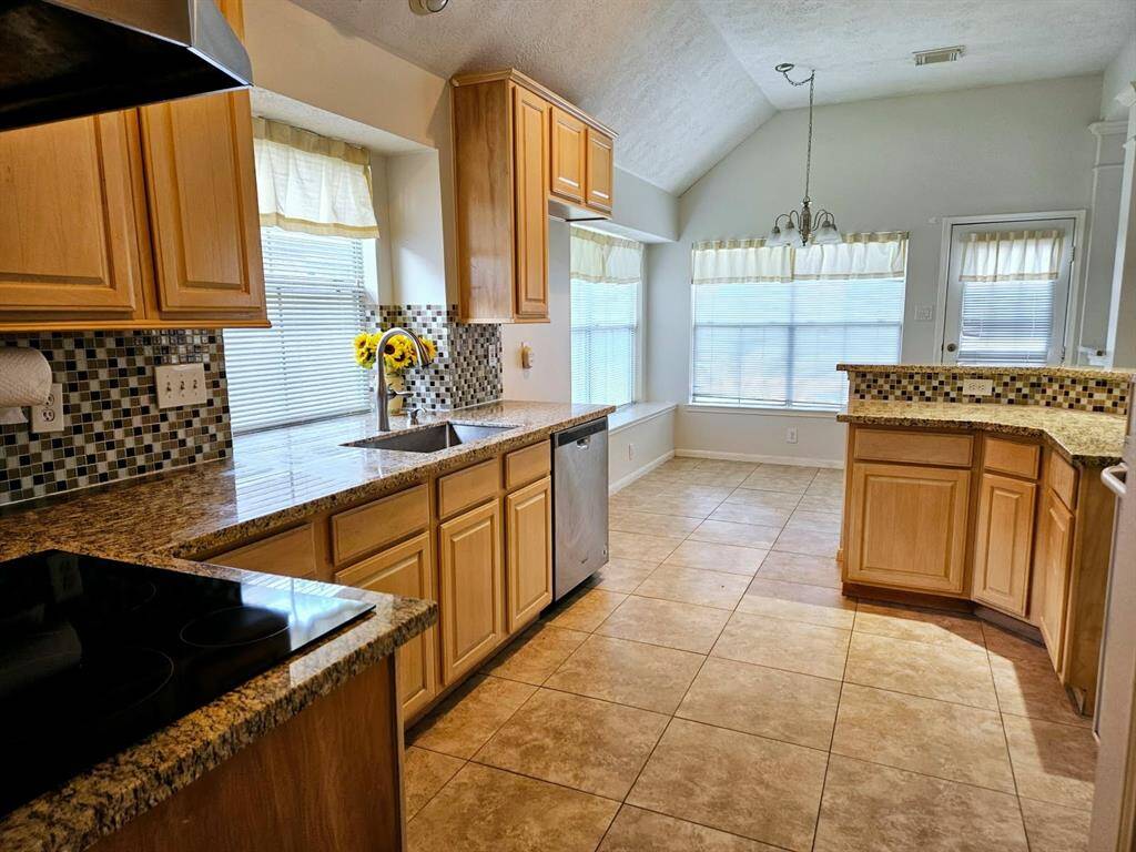 Well-appointed with ample cabinetry, this kitchen balances style and function. The textured backsplash adds visual contrast, while the breakfast bar subtly defines the space, offering a perfect spot to engage with guests in the adjoining living room. A cozy breakfast area to the side invites casual dining.