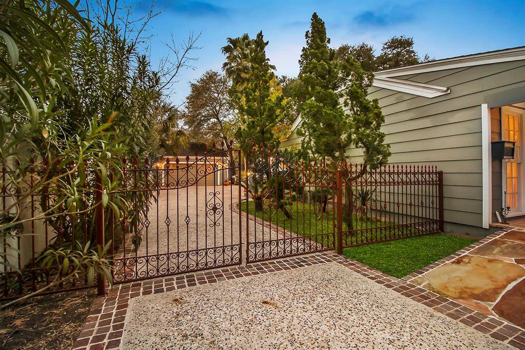 Wide side-yard provides plenty of privacy from the neighbors. A private driveway, bordered with green space and trees, leads to the two-car garage, located in the mid-section of the property. Custom built gates and fences on both sides of the house closes the property.