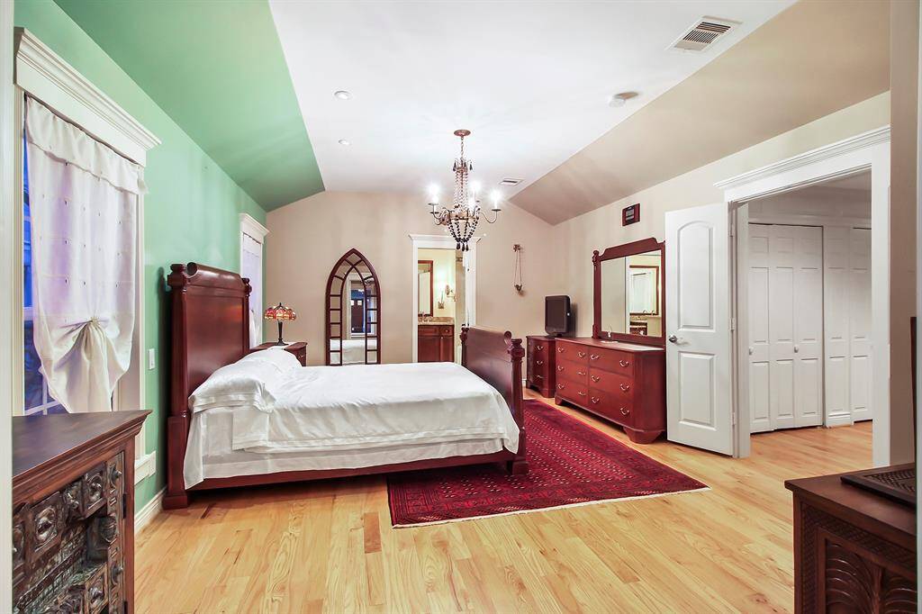 Another view of the master bedroom shows the large French door access from the hallway direction. Notice chandelier light fixture and additional spotlights