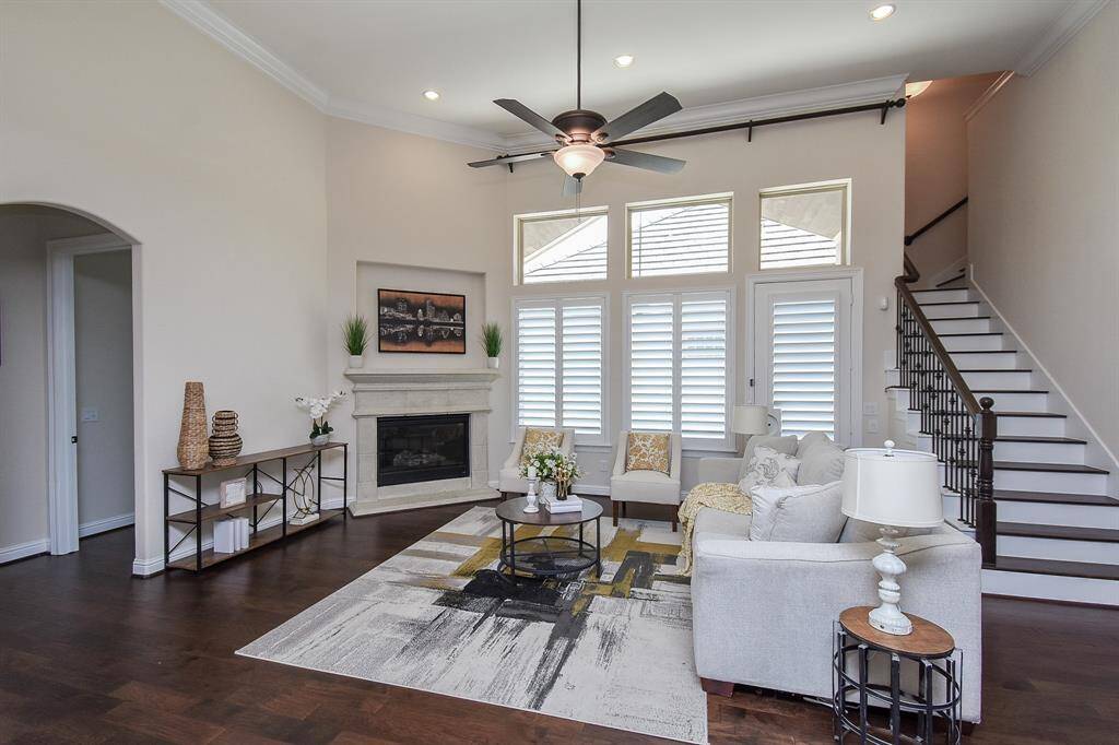 The living room boasts rich engineered hardwood floors, and abundant natural light through tall windows with plantation shutters. A gaslog fireplace adds warmth and charm, while the open layout flows effortlessly into the dining and kitchen areas.