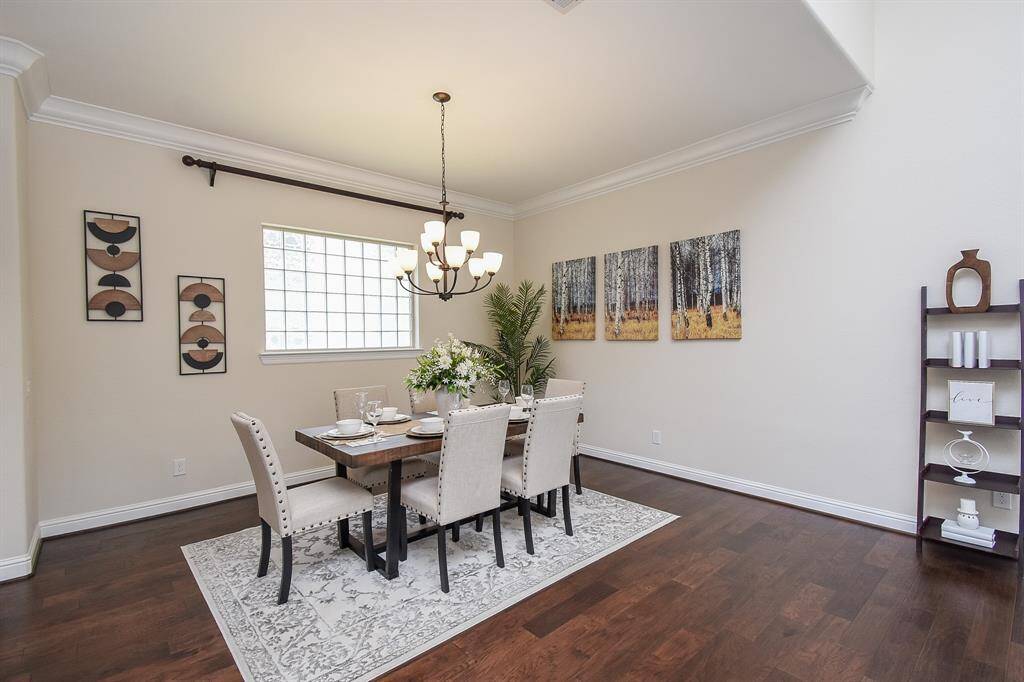 The formal dining room offers an elegant space for hosting dinner parties or enjoying meals with loved ones, complete with crown molding and a classic chandelier that elevates the room’s warmth and charm.