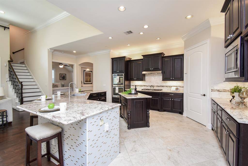This gourmet kitchen blends style and function with rich cabinetry, sleek granite countertops, a spacious island, stainless steel appliances, and a double oven—perfect for everything from morning coffee to hosting dinner with friends.