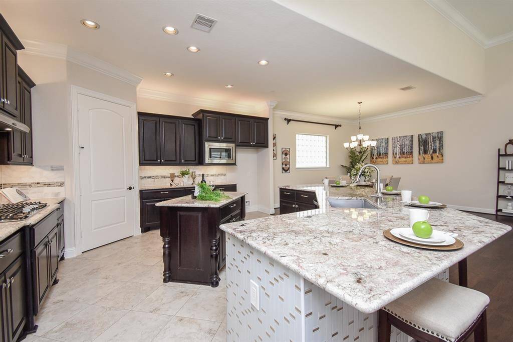 The oversized island offers extra seating and prep space, while elegant tile floors and dark cabinetry add timeless sophistication.