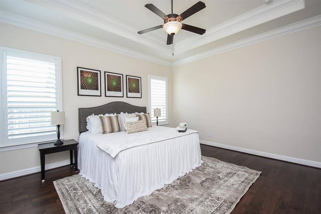 The primary suite offers a peaceful retreat with rich hardwood floors, tray ceilings, and abundant natural light. It’s the perfect space to unwind after a long day.