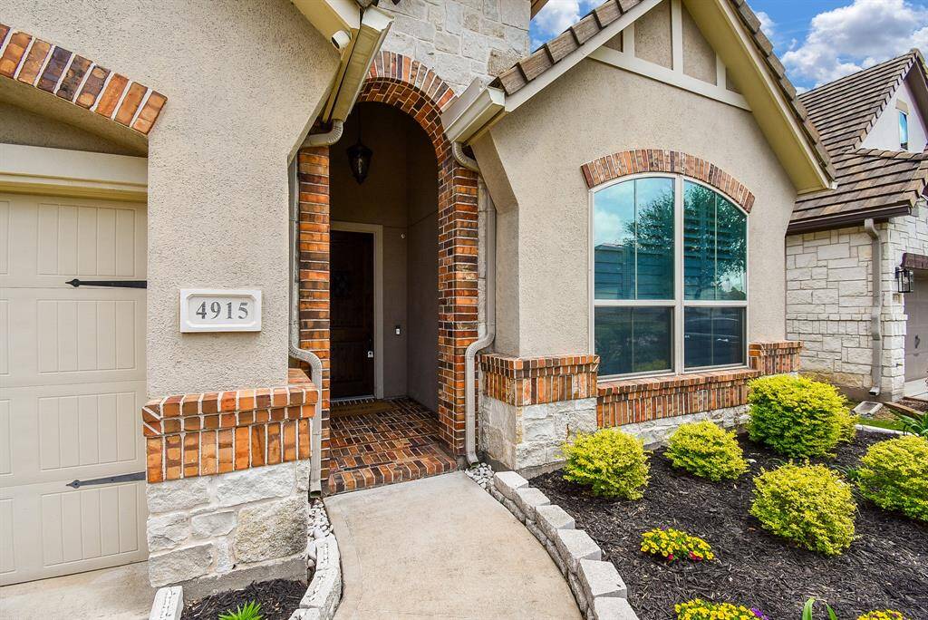 A brick and stone archway leads you through a covered front porch with rich brick flooring—setting the tone for the warm, elegant style you'll find inside this Sugar Land gem.