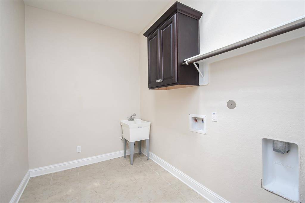 The laundry room offers plenty of space for your washer and dryer, plus a convenient utility sink, upper cabinetry for storage, and a hanging rod—making laundry days a little easier and more organized. Skylights were also added to bring in natural light and brighten the space.