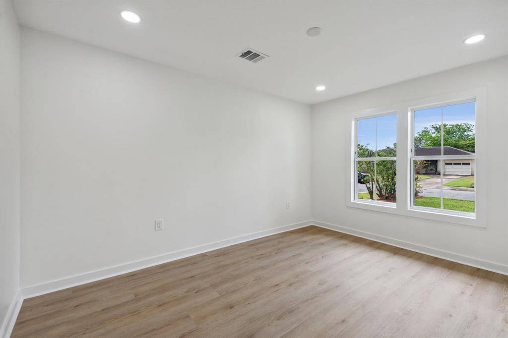 Light-filled secondary bedroom with recessed lighting and front-facing windows.