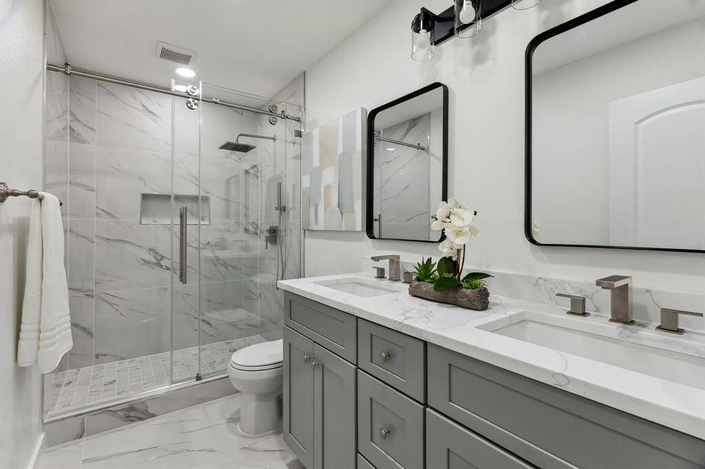 Stylish secondary bath with dual sinks and a frameless glass shower.