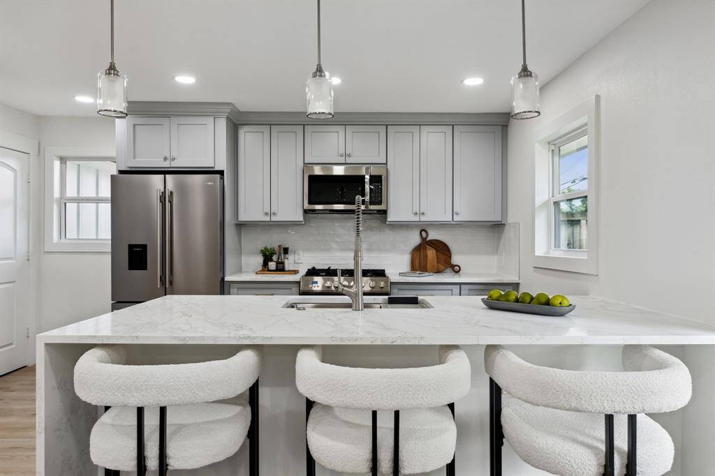 Quartz waterfall island with counter seating and views to the backyard.
