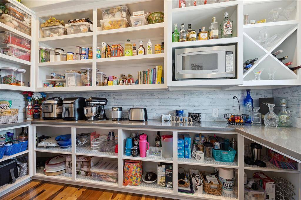 The walk-in pantry features custom storage design, custom door and additional Quartz counters