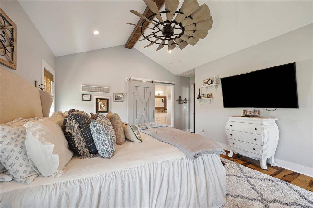 The spacious primary suite is serene coastal elegance, featuring warm Brazilian Pecan engineered flooring, a custom ceiling fan, and wood beamed ceiling accent. The large primary closet offers built-ins, shelving & the ultimate in organization and functional space for your wardrobe ensuring everything has its place