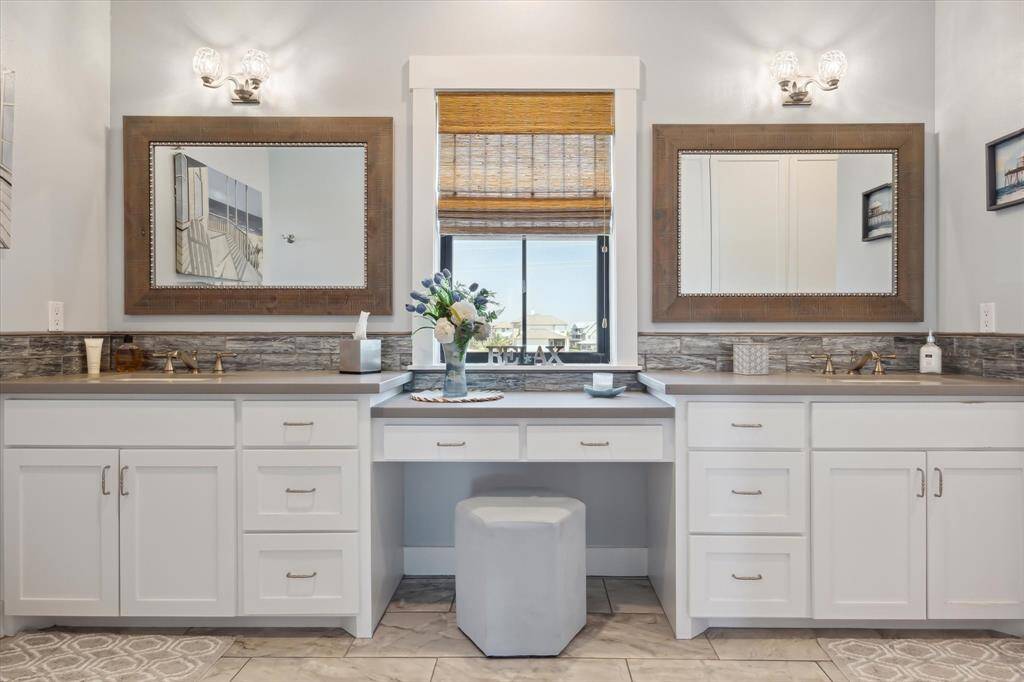 The primary ensuite bath features dual vanities, and natural light, creating a bright space. The primary bathroom boasts an impressive wall of custom cabinetry, offering both style and ample storage (not featured in this photo)