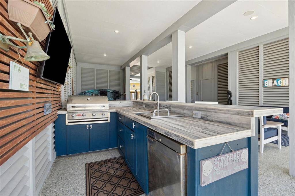 Ground level entertainment area complete with outdoor kitchen including a custom BBQ island with Bull grill, fridge, sink, and ice box. There is also a half bath on the ground level that make this space as functional as it is polished