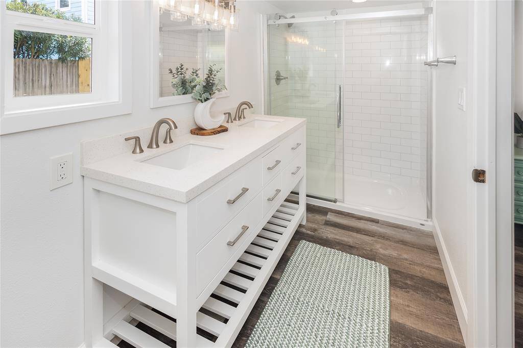 Glass-enclosed, sliding door, standing shower continues the fresh, modern aesthetic of this back home.