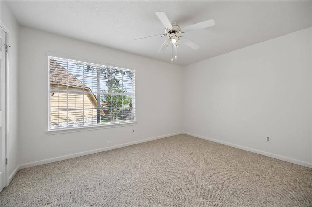 The spacious upstairs bedroom features cozy Berber carpet, a ceiling fan for year-round comfort, and plenty of room to relax or personalize.
