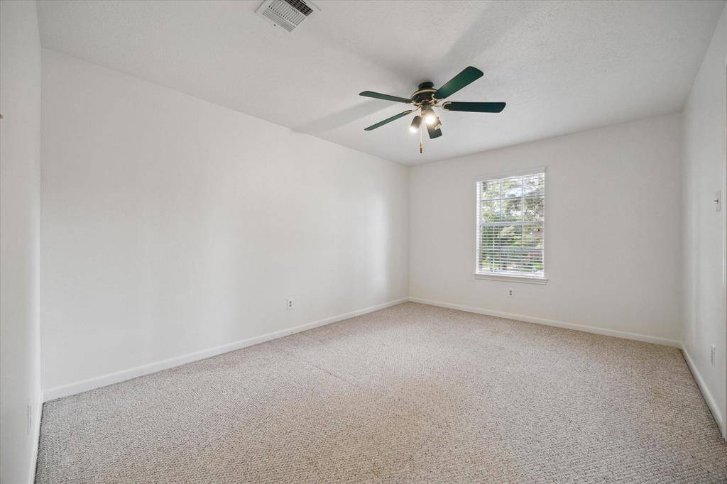 Bedroom three offers generous space with soft Berber carpet underfoot, a ceiling fan for added comfort, and plenty of room to make it your own.