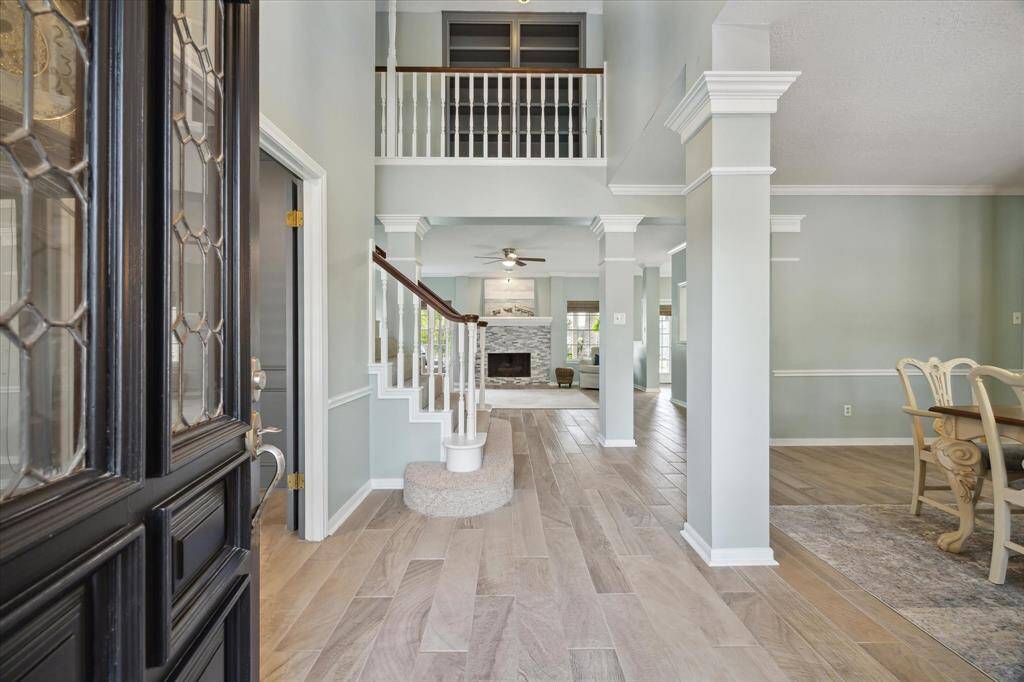 Step into an impressive entryway where your sightline extends straight into the heart of the home. Soaring ceilings showcase the open hallway above, while a formal dining room sits elegantly to the right and a private office to the left—creating a grand and welcoming first impression.
