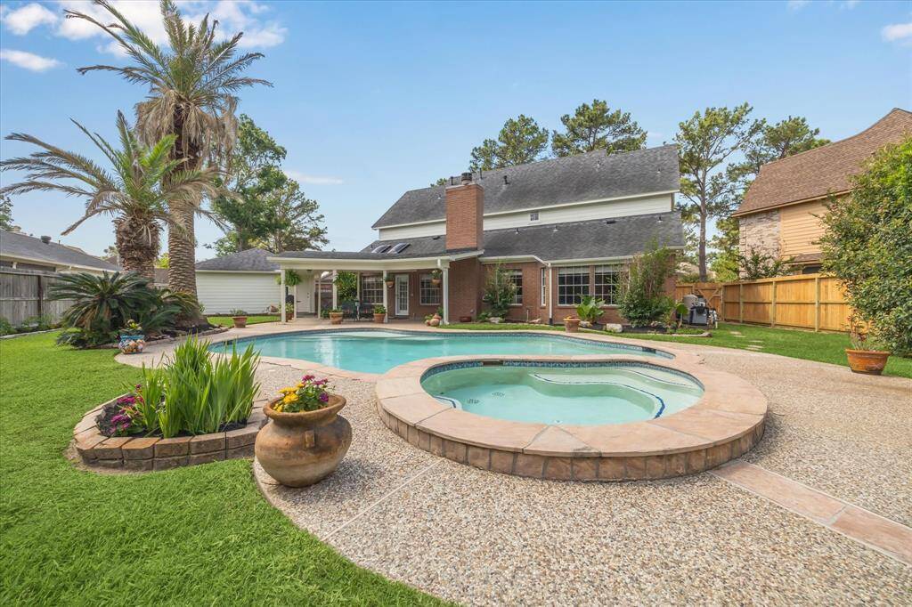 Enjoy a beautiful view from the pool and spa, looking back at the elegant rear elevation of the home and the detached three-car garage—creating a picture-perfect backdrop for outdoor living.