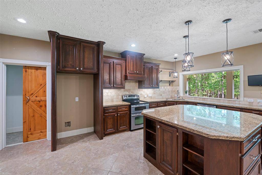 A large island kitchen with amazing views!  Gorgeous custom wood cabinets adorned with granite countertops provide ample storage that we are sure the chef of the home will just LOVE!