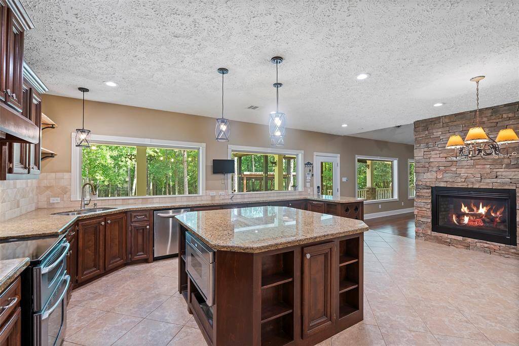 WOW!  Just look that the views in this AMAZING island kitchen!  Tons of natural light along with pendant lighting above the sink, island and just peep at that the dual sided fireplace with stone surround!  This will surely be the favorite indoor gathering space around this HUGE island, that doubles as the perfect buffet spot!