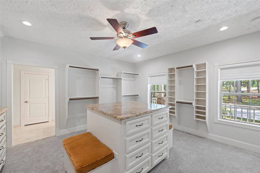 WOW! Just look at this primary closet!  Custom built with an island for storage and display, hanging storage, shoe racks, recessed lighting and once again more natural light!