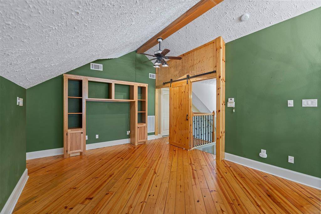As we venture upstairs, you come into this fabulous game room area with custom barn door, beautiful pine floors, custom built-in for entertainment equipment and beam to add depth!