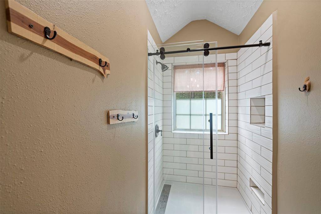 A custom glass enclosed shower with insets for all things shower, and a cozy window allowing in natural light is just perfect!