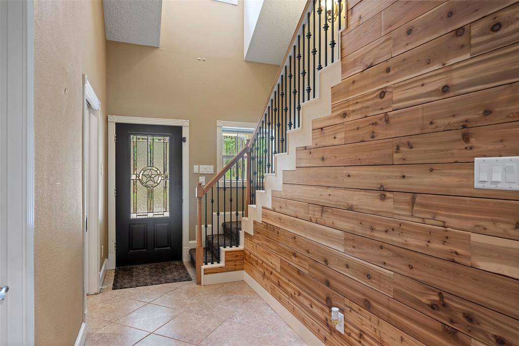 Open the door to a fabulous 2-story entryway with a timeless wrought iron staircase and wooden accent wall!