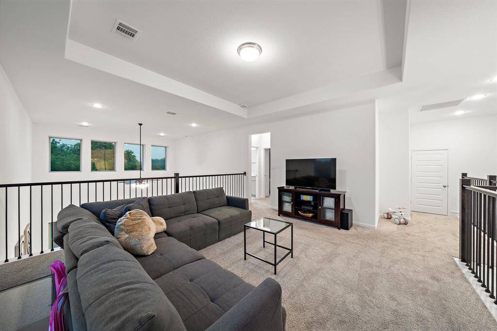 The game room features plush carpet and high tray ceilings.