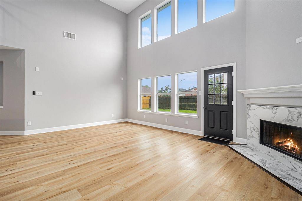 This spacious living room features high ceilings and abundant natural light from large windows.