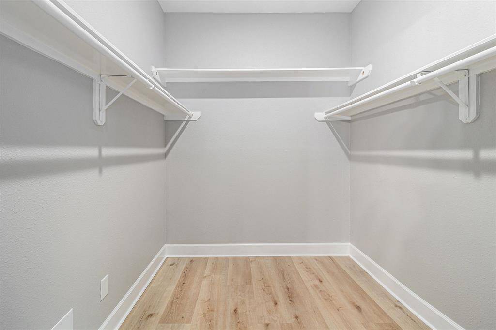 This photo shows a spacious walk-in closet with multiple white shelves and hanging rods for ample storage.