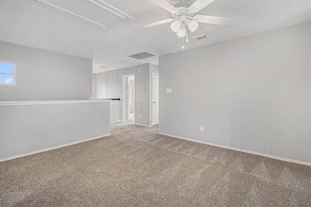 Bright, spacious room with neutral walls and carpet, featuring a ceiling fan. Ideal for a cozy living area or office space, with a small window adding natural light.