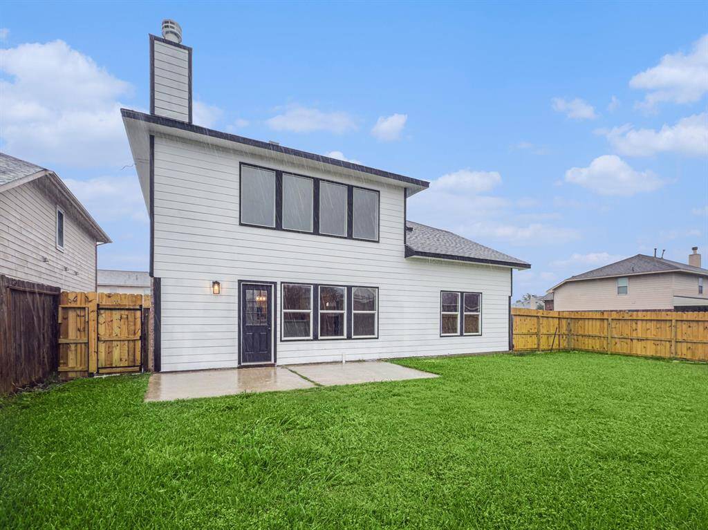 This is a two-story home with a modern white exterior and a spacious fenced backyard. It features a patio area and large windows, offering plenty of natural light and outdoor space.