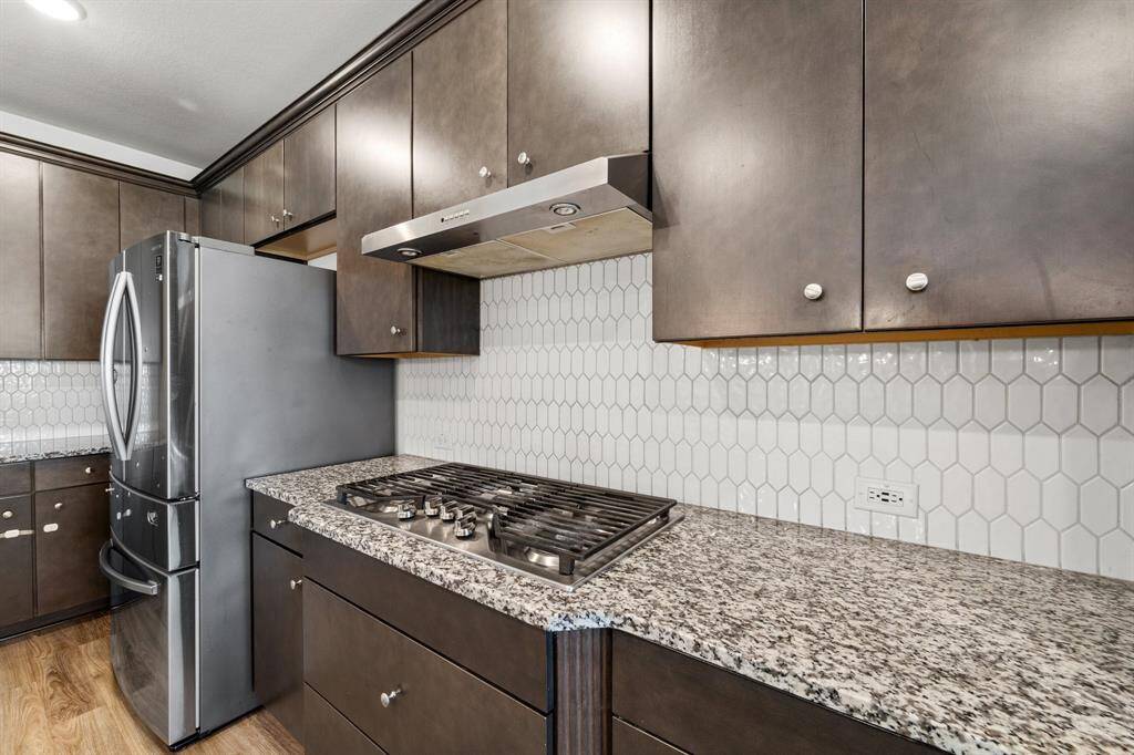 A closer look at the gourmet kitchen, featuring a 5-burner gas cooktop, granite counters, and a custom tile backsplash with extended cabinetry.