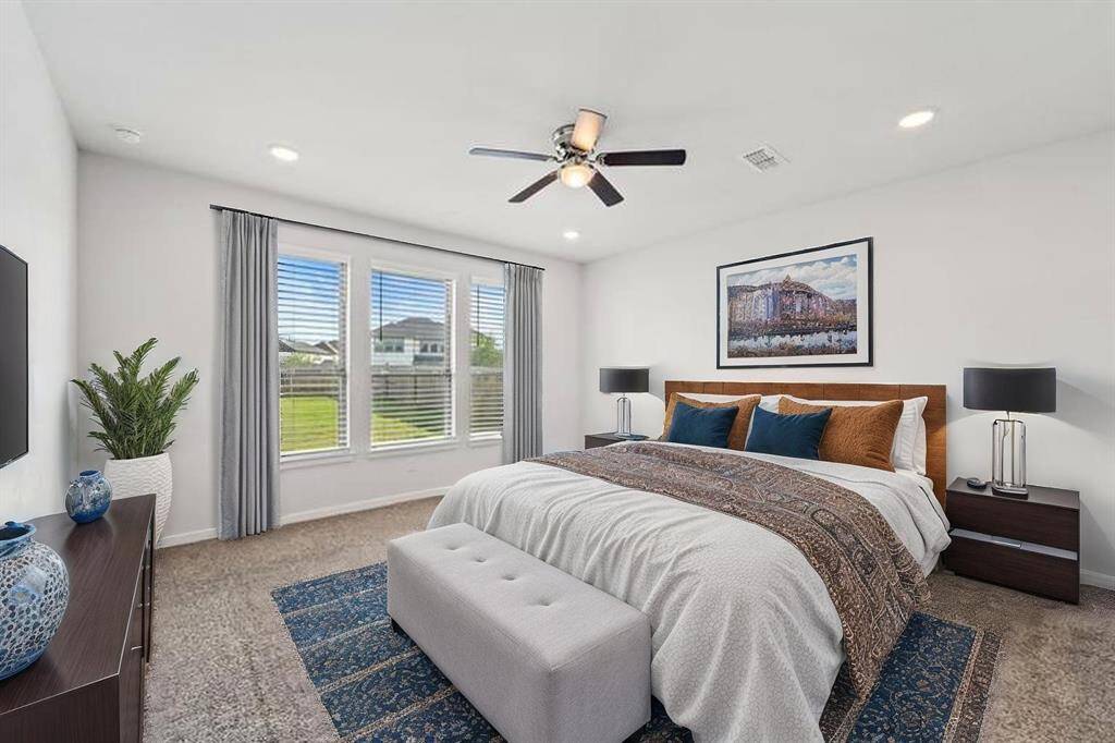 This oversized primary suite offers plenty of space for a seating area or additional furniture, complemented by plush carpeting and recessed lighting. Natural light pours in through three large windows that offer a serene backyard view. (Virtually Staged)