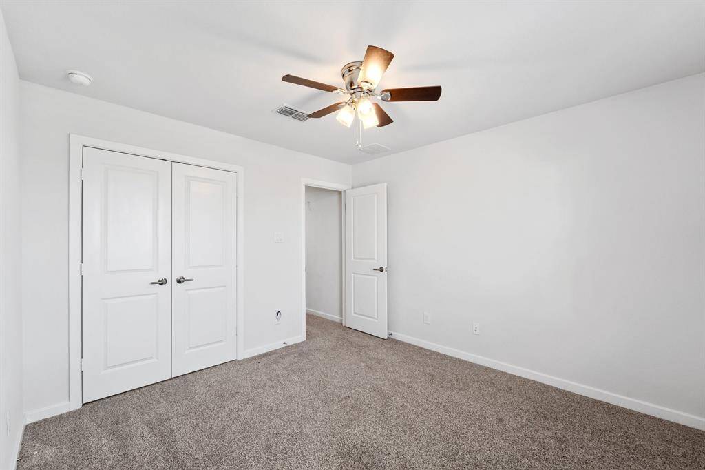 Opposite view of the same bedroom highlighting the spacious closet and ceiling fan for comfort.