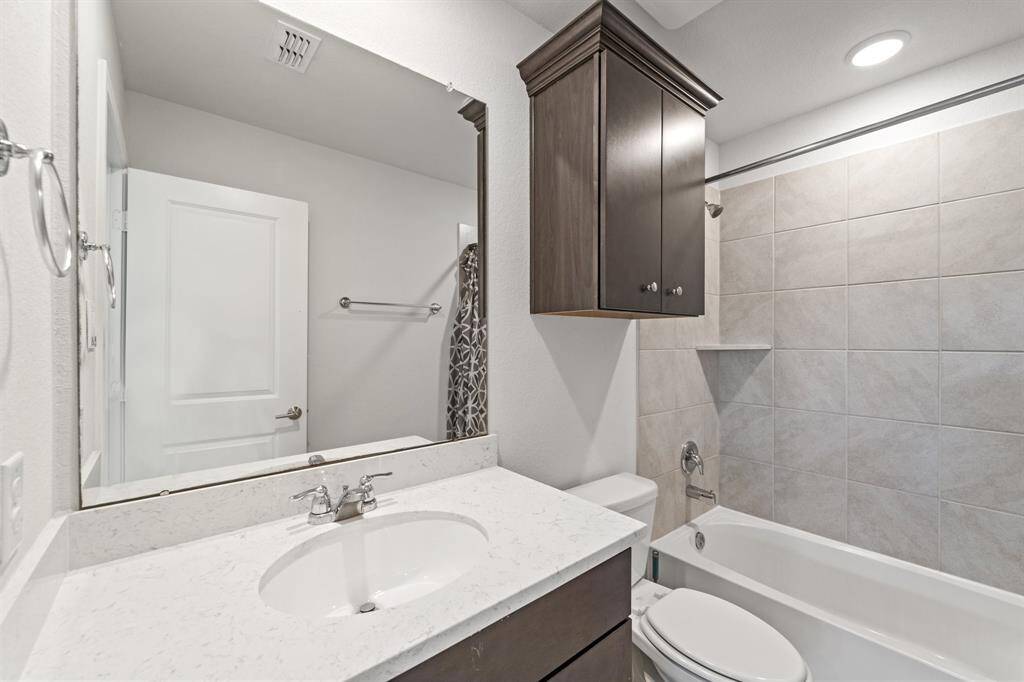 Full bathroom with a tub/shower combo, gorgeous countertop, and overhead storage cabinet.