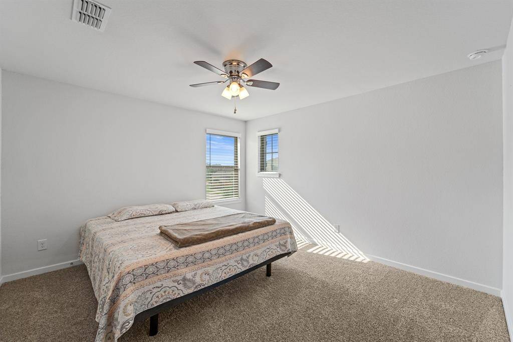 Spacious upstairs bedroom offering dual windows, ample light, and a relaxing atmosphere.